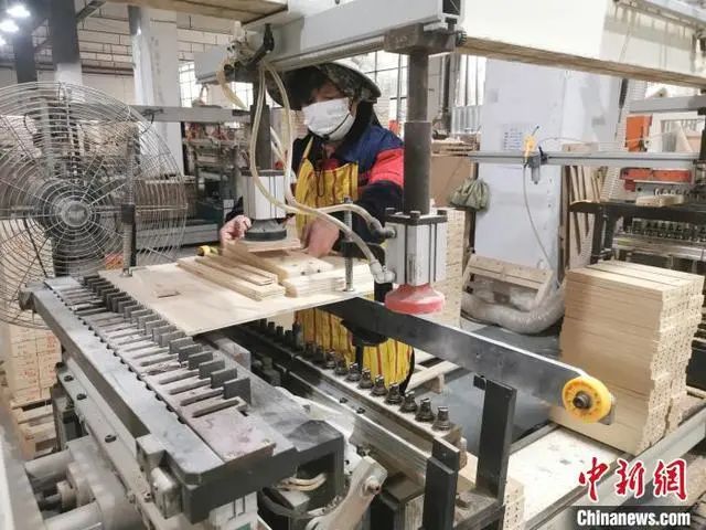 工人正在對原木板材進行打孔處理